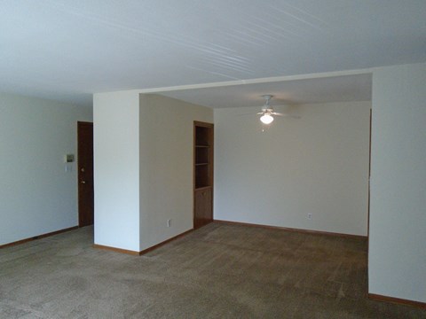 an empty living room with white walls and a ceiling fan